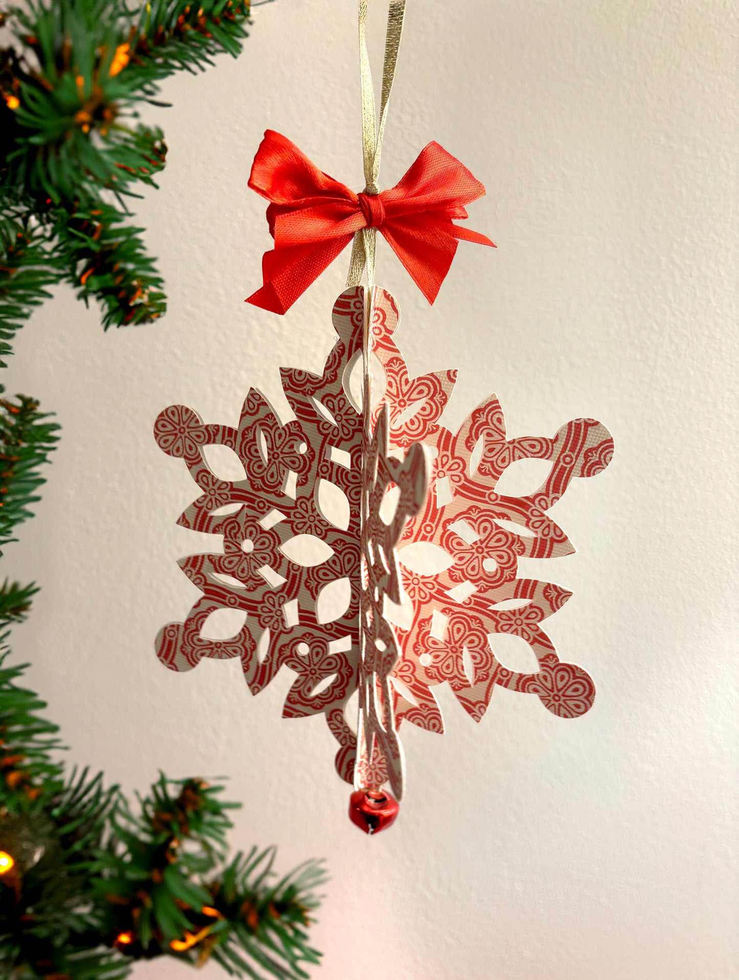 Christmas paper cutout snowflake with red satin ribbon and bell